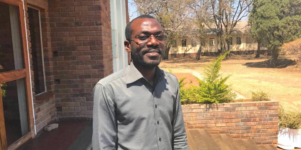 Angolan theology student Paulo Pinto standing outside the main administration building at Solusi University in Zimbabwe. (Andrew McChesney / Adventist Mission)