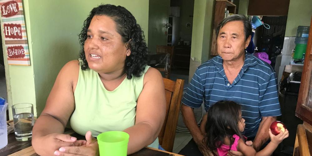 Olga Chee reflecting on her married life as her husband, Johnny, holds a granddaughter in their home in Orange Walk, Belize. (Andrew McChesney / Adventist Mission)