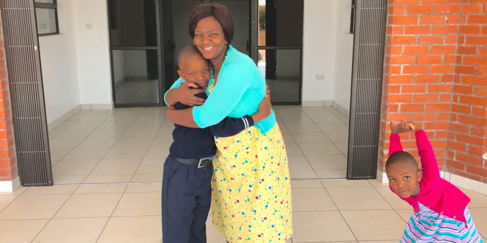 Gomolemo Masienyne embracing her son, Lethabo, as her daughter, Resego, stands nearby at the entrance of Eastern Gate Primary School in Francistown, Botswana. (Andrew McChesney / Adventist Mission)