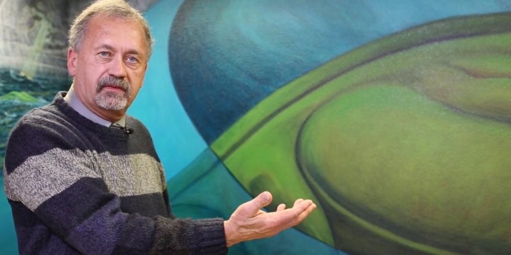 Stan Hudson, 65, gesturing near a mural painted by his former roommate, David L. Friend, at the Creation Study Center in Ridgefield, Washington. (NPUC)
