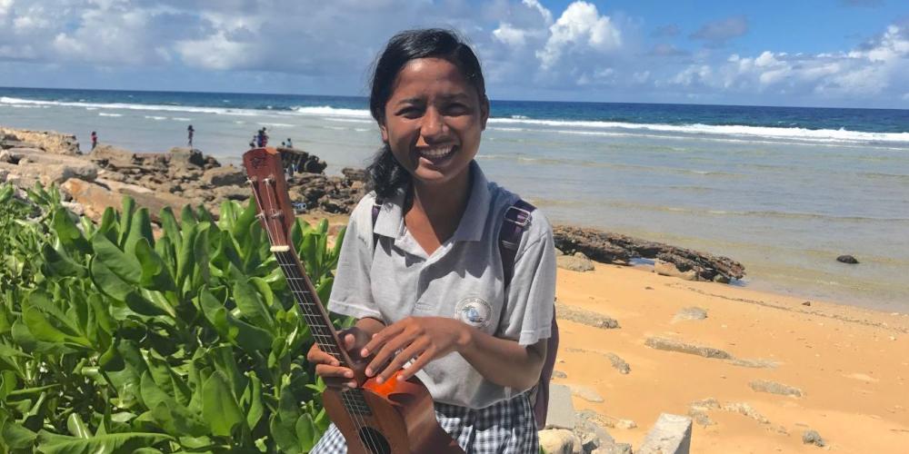 Viona Boro, 16, holding her ukulele on a beach on Ebeye Island. (Andrew McChesney / Adventist Mission)