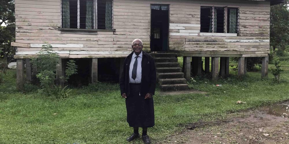 Joeli Rabo, 67, standing outside a typical home in the area of rural Fiji where he is planting his third church. (Andrew McChesney / Adventist Mission)