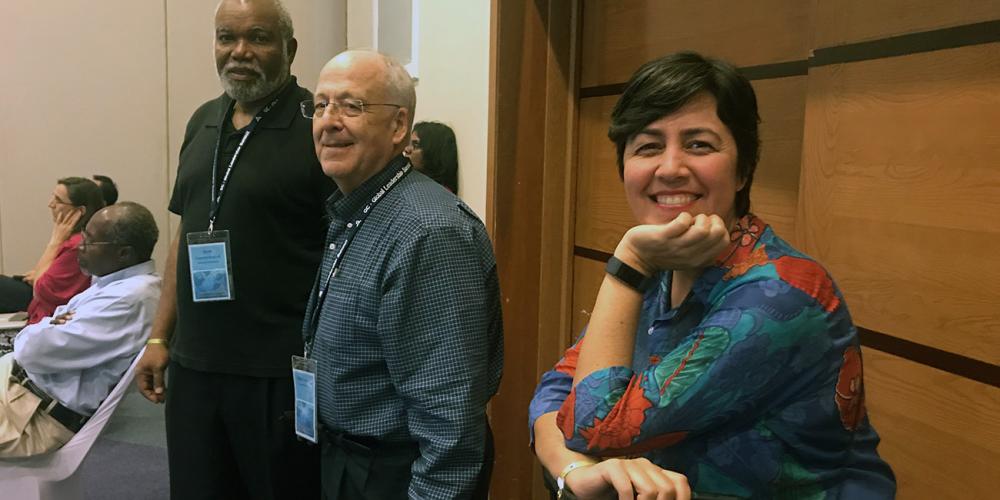 Peter N. Landless, center, health ministries director for the Adventist world church, standing with his associate directors Katia Reinert, right, and Zeno L. Charles-Marcel at the back of a hotel conference hall during the 12th Global Leadership Summit in Montego Bay, Jamaica, on Feb. 3, 2019. (Andrew McChesney / Adventist Mission)