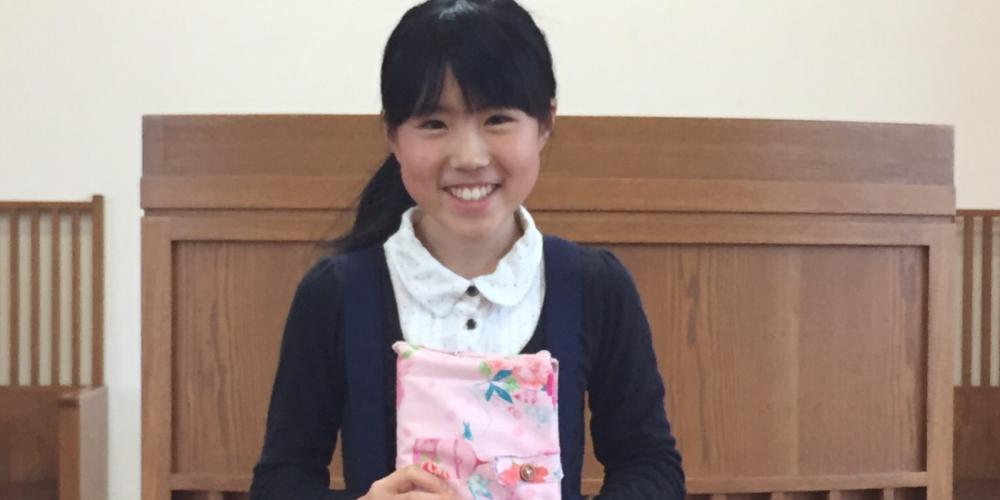 Taniguchi Iku, 12, holding the Bible that she received from her grandmother in the first grade. (Family photo)