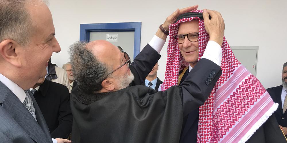 A special guest, Dr. Hamdi Murad, placing a traditional headscarf on Seventh-day Adventist Church president Ted N.C. Wilson while chief architect Mazen W. Shaban, left, who presented the gift, smiles with approval at Adventist National School in Amman, Jordan, on Wednesday, Jan. 29, 2020. (Andrew McChesney / Adventist Mission)