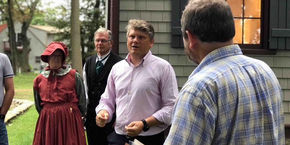 Markus Kutzschbach, director of Adventist Heritage Ministry, speaking to General Conference visitors outside the Joseph Bates house in Fairhaven, Massachusetts, on Sept. 12, 2018. To the left are house caretakers Lloyd and Dora Hallock, wearing period dress. (Clinton Wahlen)