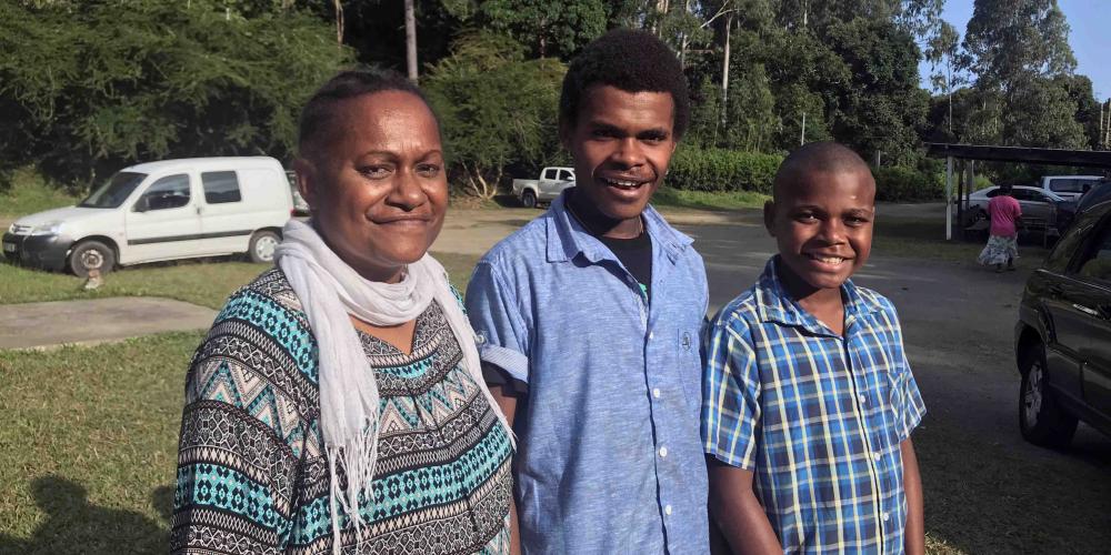 Annie Paama, 48, with her two sons. Standing in the center is Leonce Junior, who was 8 months old at the time of the storm. (Andrew McChesney / Adventist Mission)