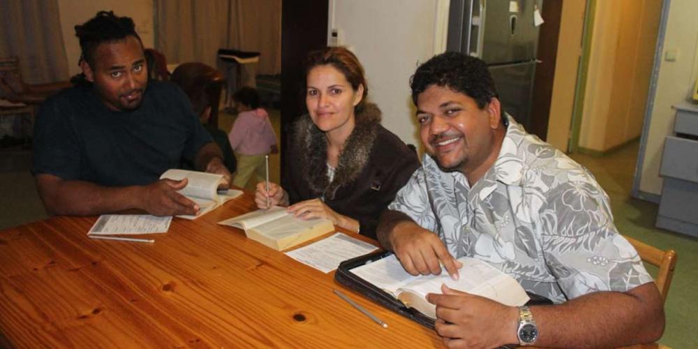 Stanislas Weneguei and his wife, Kedsia, studying the Bible with pastor Danick Adeline, left. (Adventist Record)