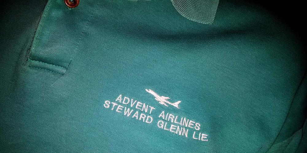 Embroidered on the left breast of Glenn Lie’s shirt are the words, “Advent Airlines, Steward Glenn Lie,” and the image of a jet plane. (Courtesy of Glenn Lie / Adventist Mission)