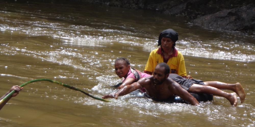 Veai Apkas reaching for a cane to pull himself and two passengers to shore in the fast-flowing Waghi River in Papua New Guinea in June 2018. (All photos: Eastern Highlands Simbu Mission)