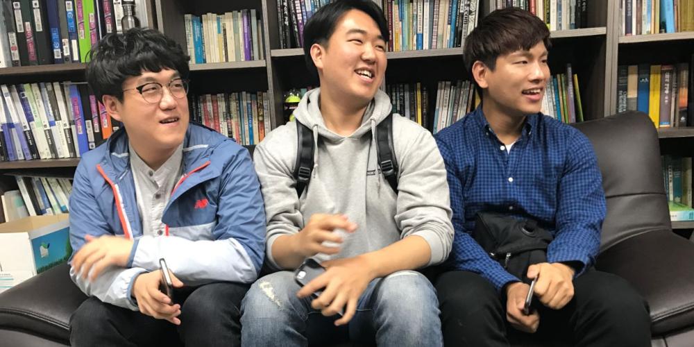 Sahmyook University students Hyunho Kim, left,Taegyun Bong, center, and Hansu Hyun discussing their efforts to reach out to Korean young people. (Andrew McChesney / Adventist Mission)