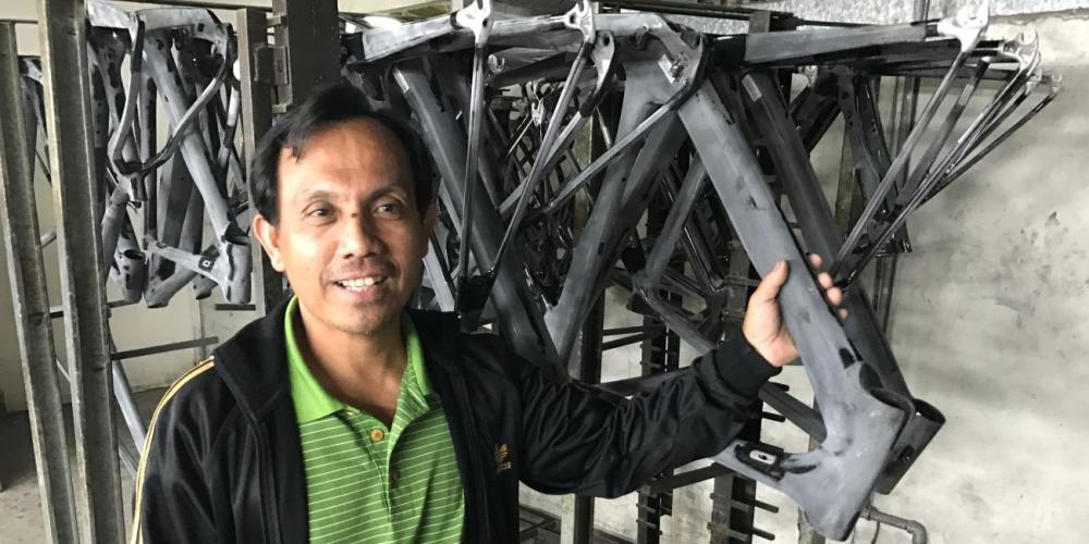 Jin Rong Gao showing some of the metal bicycle frames that are ground and polished at his workshop in Shih-kang, Taiwan. (Andrew McChesney / Adventist Mission)
