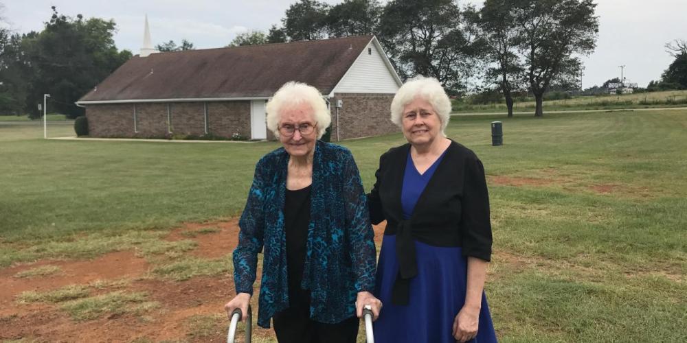 Notley Tidwell’s granddaughter Lorena Stigaullde, 94, and great-granddaughter Reba Seifert, 68, standing outside the Linden Seventh-day Adventist Church in Linden, Texas. (Andrew McChesney / Adventist Mission)