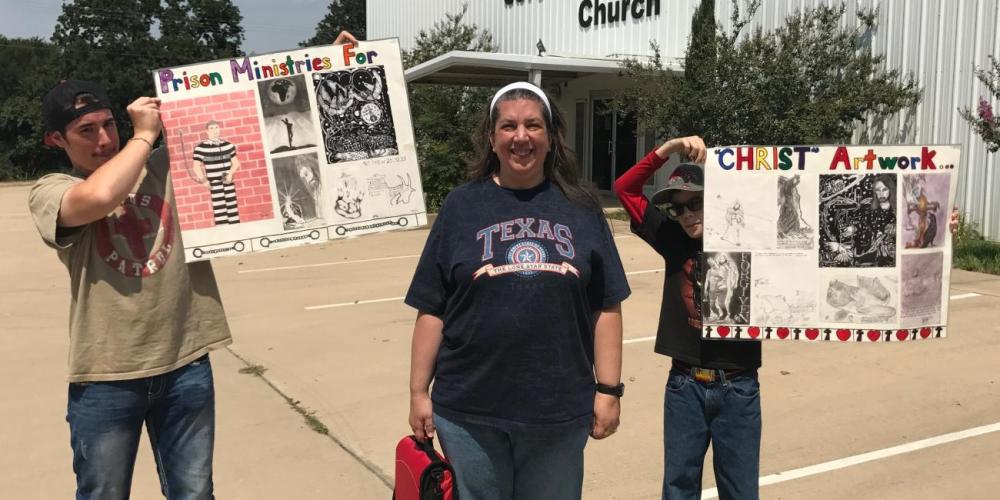 Tracey Lee with her two sons outside Grandview Seventh-day Adventist Church in Grandview, Texas. The boys are holding inmates’ drawings. (Andrew McChesney / Adventist Mission)