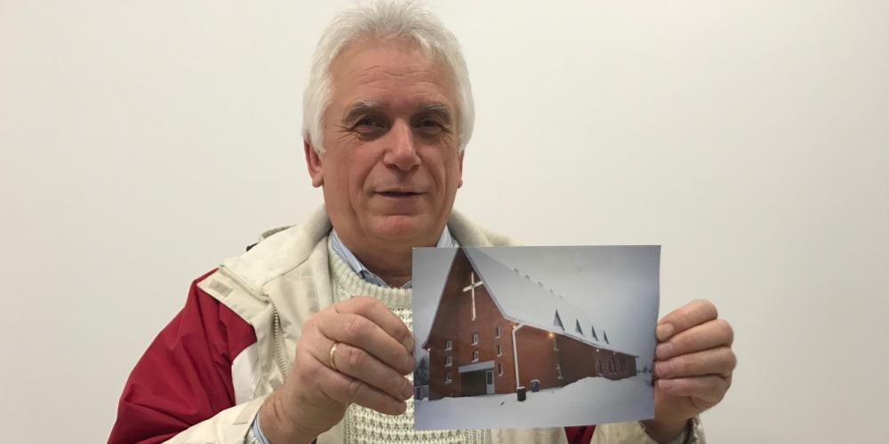 Vladimir Vlodovskyy holding a photo of the miracle church that he built in the northern Russian seaport of Arkhangelsk. (Andrew McChesney / Adventist Mission)