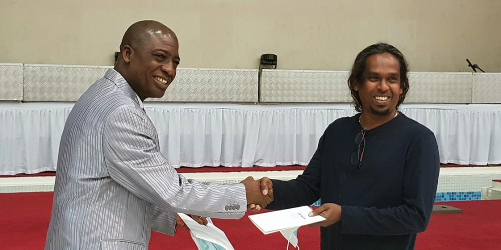 Pradeep Liyanage, right, holding his baptismal certificate as he shakes pastor Muyi Oyinloye's hand at the Seventh-day Adventist church in Sharjah, United Arab Emirates, on March 13, 2021. Photo by Middle East and North Africa Union