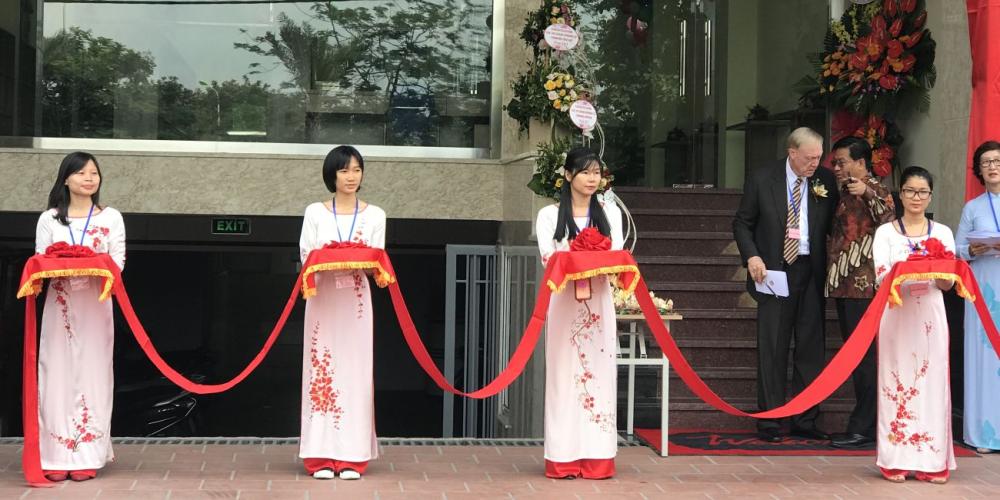 Jannie Bekker, in striped tie, who played a key role in the opening of the Forward Venture community center, speaking with Samuel Saw, president of the Southern Asia-Pacific Division, at an inauguration ceremony in Hanoi, Vietnam, on May 22, 2018. Women wearing traditional Vietnamese costumes are holding a red ribbon to be cut by church leaders. (All photos: Andrew McChesney / Adventist Mission)