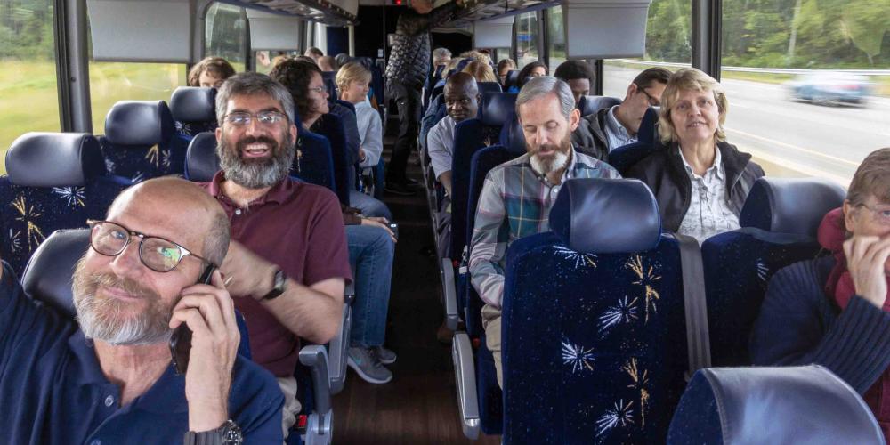 General Conference leaders, including president Ted Wilson, left, and assistant to the president Magdiel Perez Schulz, second left, traveling on a bus during a church heritage tour in the U.S. Northeast on Sept. 11, 2018. (Andrew McChesney / Adventist Mission)