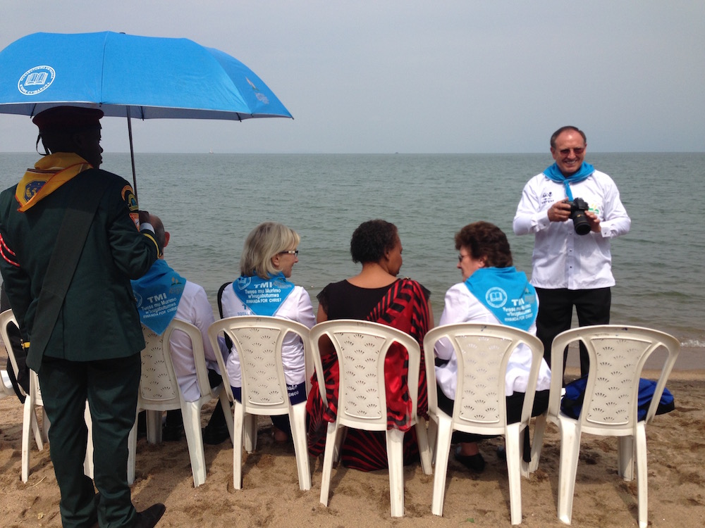 Duane McKey, standing right, taking photos of a mass baptismal ceremony at Rwanda's Lake Kivu in May 2016. (Andrew McChesney / Adventist Mission)