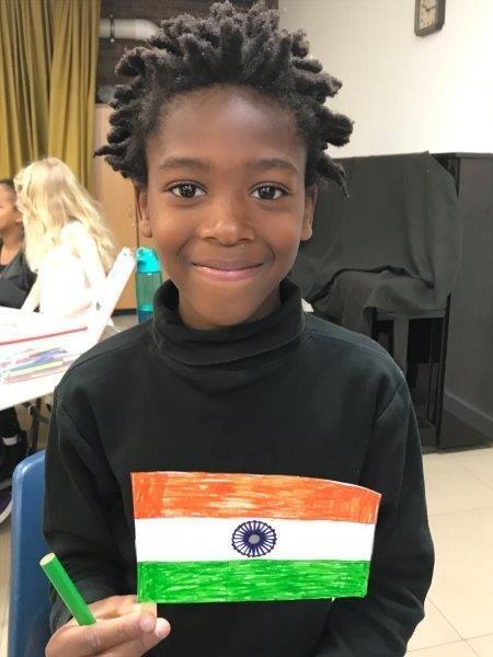 A child showing a colored Indian flag. National flags for coloring are featured in the back of the Children’s Mission  magazine.