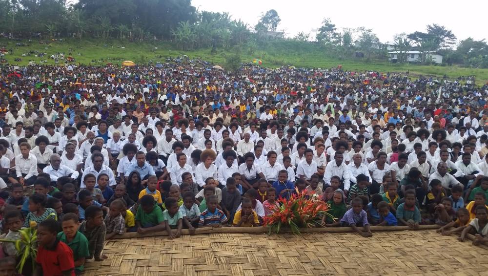 Baptismal candidates, in white, posing with other attendees at the camp meeting.