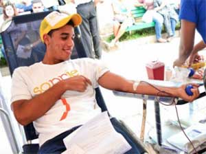 A church member volunteer donates blood while sporting his “Smile God Believes in You” T-shirt during a massive blood drive during the week of Aug. 4-10, 2013.