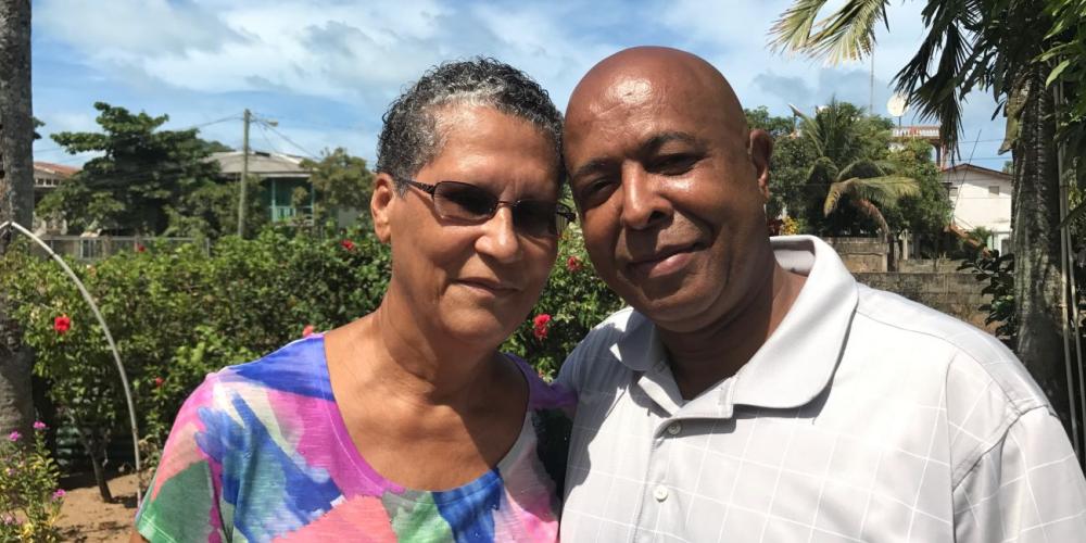 Louise and James Pescascio standing in the yard of their home in Dangriga Town, Belize. (Andrew McChesney / Adventist Mission)